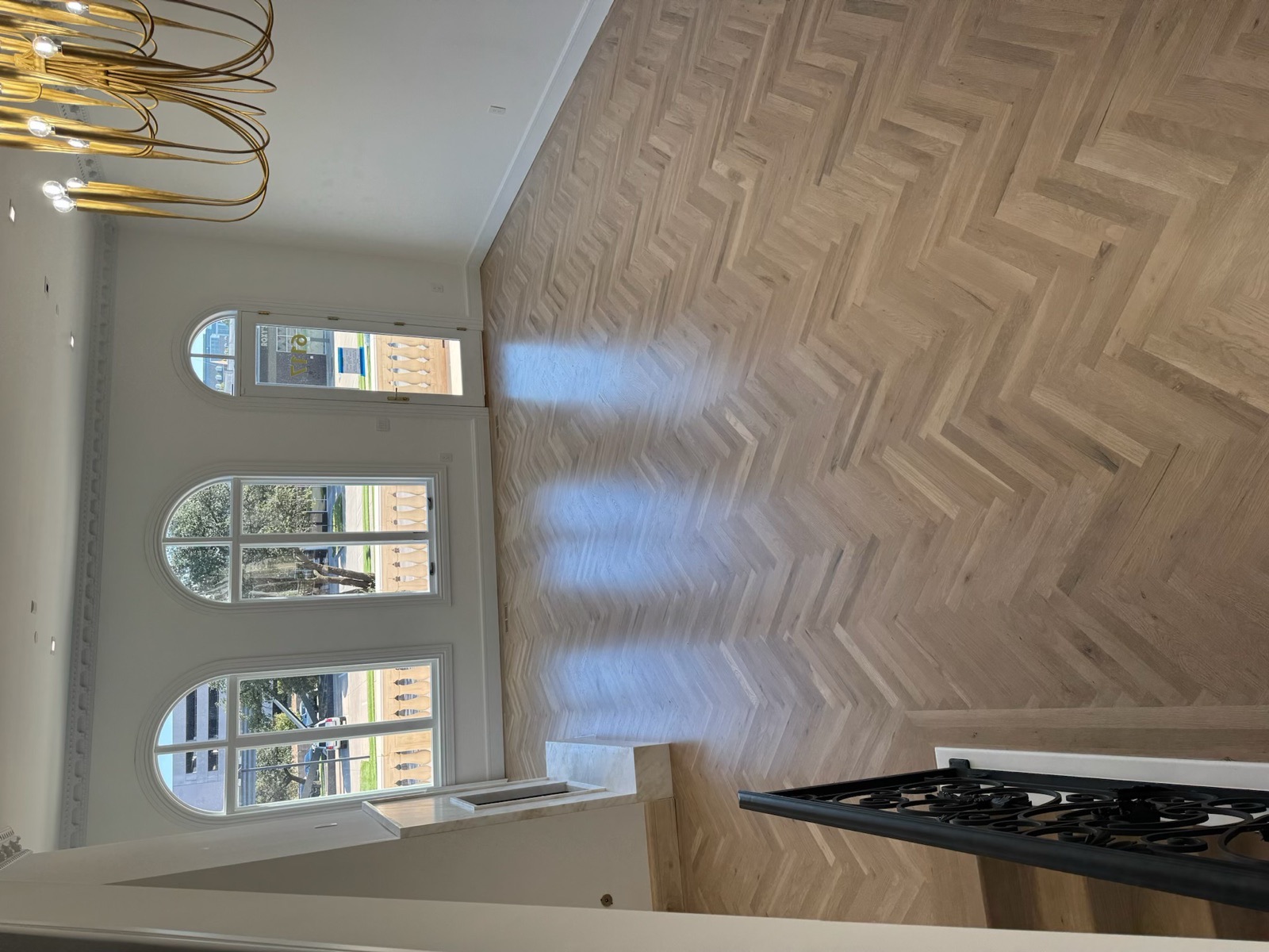 White oak herringbone floor in an entryway with arched windows